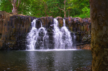 Rochester Falls in Mauritius with water cascading over basalt columns into a calm pool, surrounded by tropical forest.