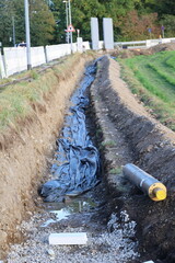 Pipe is laying on the ground next to a trench