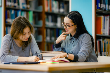 Female researchers discussing findings while reading academic books at library table knowledge exploration research concept.