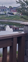 Houses reflected in the lake with a wooden railing