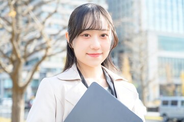 オフィス街でノートパソコンを持つビジネスウーマン