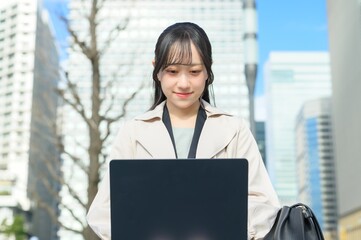 オフィス街でノートパソコンを持つビジネスウーマン