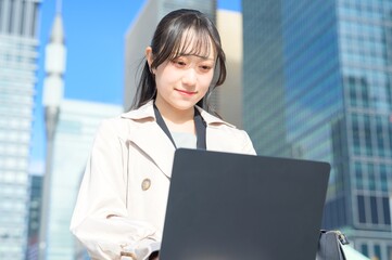 オフィス街でノートパソコンを持つビジネスウーマン