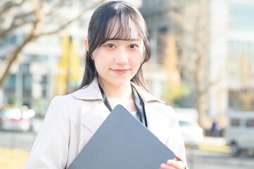 オフィス街でノートパソコンを持つビジネスウーマン