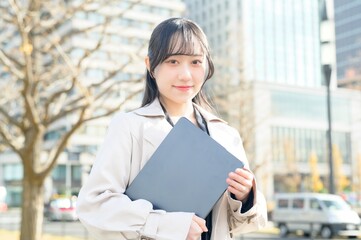 オフィス街でノートパソコンを持つビジネスウーマン