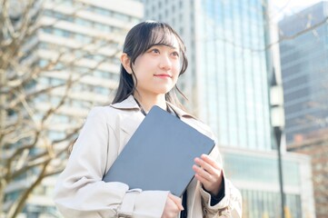 オフィス街でノートパソコンを持つビジネスウーマン