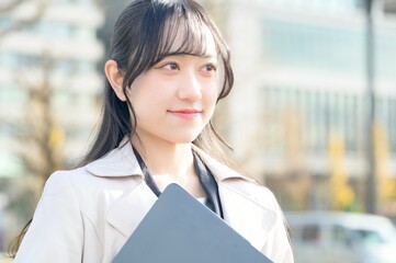 オフィス街でノートパソコンを持つビジネスウーマン