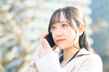 オフィス街でスマホを使用する20代のビジネスウーマン