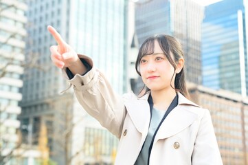 オフィス街で指差しをする日本人ビジネスウーマン