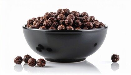 Fototapeta premium Black bowl filled with whole black peppercorns on white surface with scattered peppercorns around base.