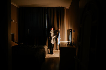Young woman ironing a shirt in a dimly lit room during the evening
