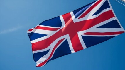 Close-up of the United Kingdom Union Jack flag waving in the breeze against a clear blue summer sky, symbolizing British national pride