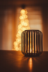 Christmas candle and Christmas lights. In background Christmas tree.
