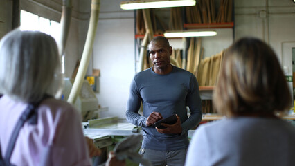 Male woodworker consulting clients using a digital tablet