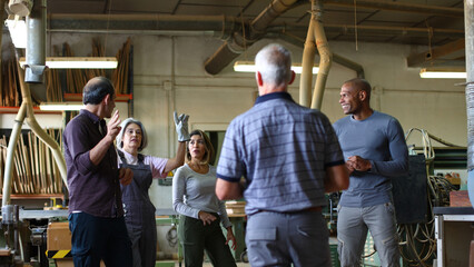 Diverse adults discussing project in woodworking workshop