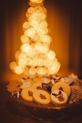 Christmas cookies close up. Christmas cookies on a glass tray. In background Christmas tree. Christmas lights.