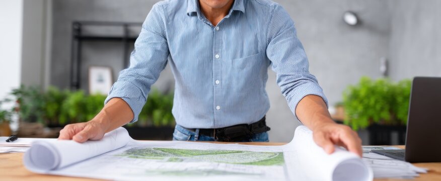 landscape architect reviewing intricate blueprints at their desk