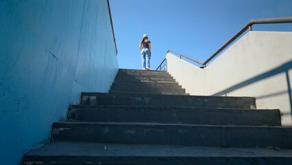 Young woman in a blue T-shirt and jeans walking up the stairs