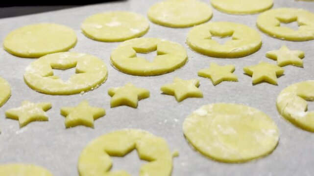 Homemade Alsatian bredele cookie dough cut into star and round shapes on parchment-lined baking tray, lightly floured and ready to bake for Christmas holiday treats