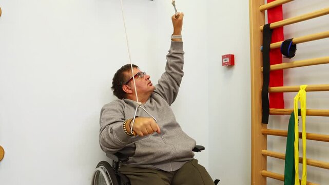 Disabled man in wheelchair exercising with pulley during physical therapy