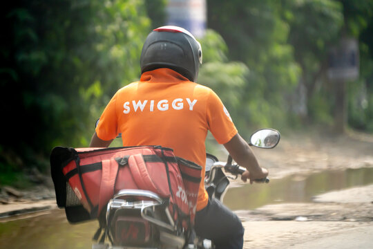 Food delivery rider from Swiggy with a zomato bag showing the multi hatting with food technology apps that the gig workers do to ensure sustainable income
