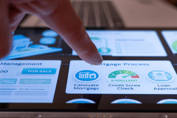 Human finger tapping on a tablet screen, accessing a digital application displaying various options for mortgage calculation, credit score checking, and loan approval services in real estate
