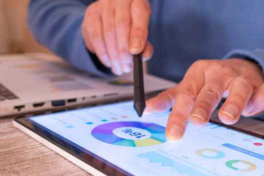 Person using a digital stylus and finger to interact with a tablet displaying a financial data dashboard with charts and graphs, showcasing modern tax planning and calculating strategies - Powered by Adobe