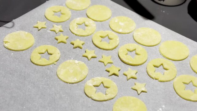 Homemade Alsatian bredele cookie dough cut into star and round shapes on parchment-lined baking tray, lightly floured and ready to bake for Christmas holiday treats