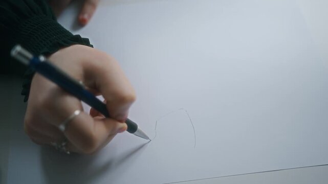 Close-up of a person starting a sketch with a pen on white paper, capturing creativity, concentration, and artistic expression.  
