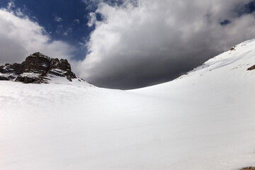 Snowy mountain pass and sky with storm clouds