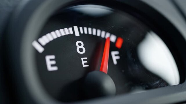 Fuel gauge needle near full with dashboard reflection shallow depth of field closeup of fuel meter showing red indicator numeric marking empty fuel gauge close up vehicle dashboard low level red