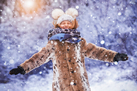 Winter Child Fun Outdoor. Joyful Happy Kid Girl Having fun in Winter Holiday in Snowy Park.  