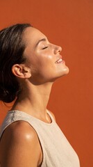 Profile of woman basking in bright sunlight against orange background