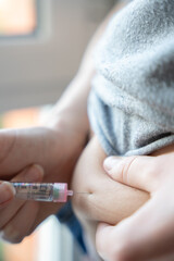 Close-up of a person giving an insulin shot in the abdomen