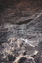 Geological formations display dark rock with white streaks along the coastline. The scene captures natural textures and patterns created by the elements over time