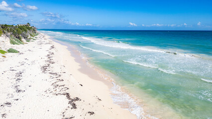 Sian Kaan Biosphere Mexico Beach with a clear blue ocean and a few small waves. The beach is sandy and the water is calm