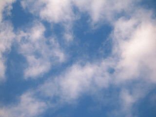 Obraz premium White cloud patches drifting through blue sky with generous copy space