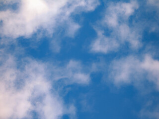 Fototapeta premium Heavenly background with light cumulus clouds scattered across the bright blue horizon