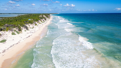 Sian Kaan Biosphere Mexico Beautiful beach with a clear blue ocean and white sand. The waves are crashing against the shore, creating a peaceful and serene atmosphere. The beach is empty, allowing for