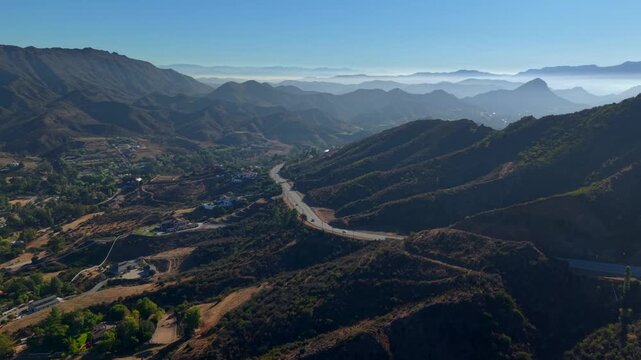 Driving Through Mountain Valley - Malibu Canyon Road in Santa Monica Mountains, California. Sunrise Drone view of a winding mountain roads between the coast and inland valleys.