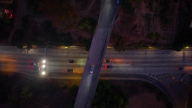 Car driving at night on overpass above highway. Looking down at Headlights shining on road as cars drive on 5 lane highway. Exit, On-ramp, Off-Ramp in the evening.