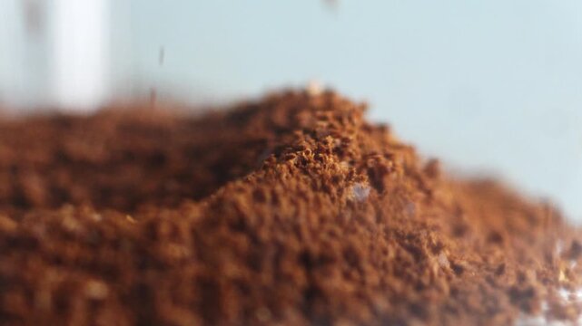 Slow motion footage of ground coffee falling into a growing pile in a kitchen or caf&eacute; environment, highlighting texture, freshness, aroma and the coffee preparation process