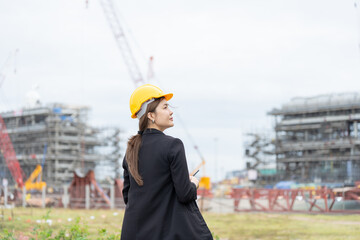 Asian female engineer supervising heavy machinery at an industrial site, representing a modern company focused on business growth, professional engineering management, and long term industry success.