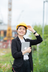Asian female engineer using radio communication at an industrial site, representing a professional company that integrates business management, machinery coordination, and engineering expertise.