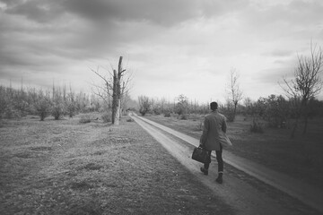 Elegant man in a stylish coat and suit holding a premium leather travel bag. Conceptual photography of business travel, fashion, and professional lifestyle.