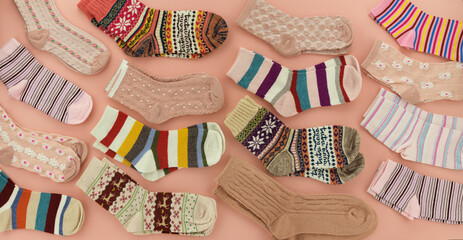 Lots of socks on a pink background. Colorful, bright socks are scattered across the surface. Clothes for fall and winter.
