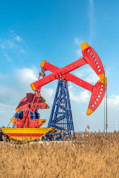Oil Pump Jack in Yellow Wheat Field Under Blue Sky