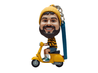 A playful bobblehead-style figure rides a bright yellow scooter, sporting a yellow beanie and striped shirt. The blue strap adds a quirky, collectible vibe perfect for gifts and decor. key ring

