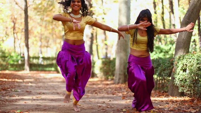 Two indian women performing bollywood dance in autumnal park