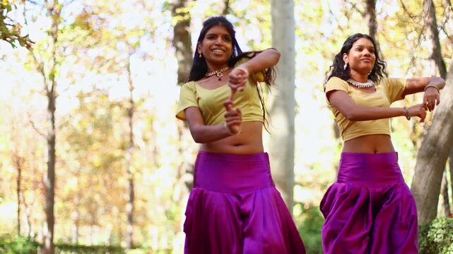 Two indian women performing bollywood dance in a forest